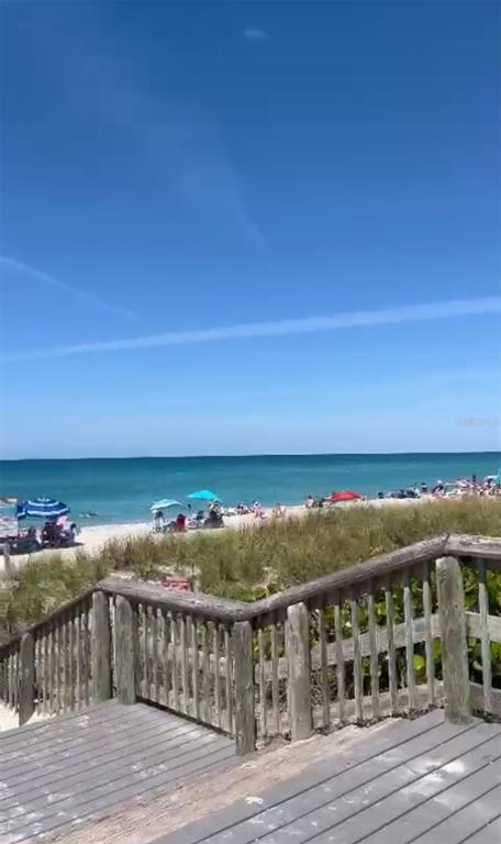 A wooden staircase leads down to a sandy beach with umbrellas and the ocean — 12152 JUDSON AVENUE, PORT CHARLOTTE, FL