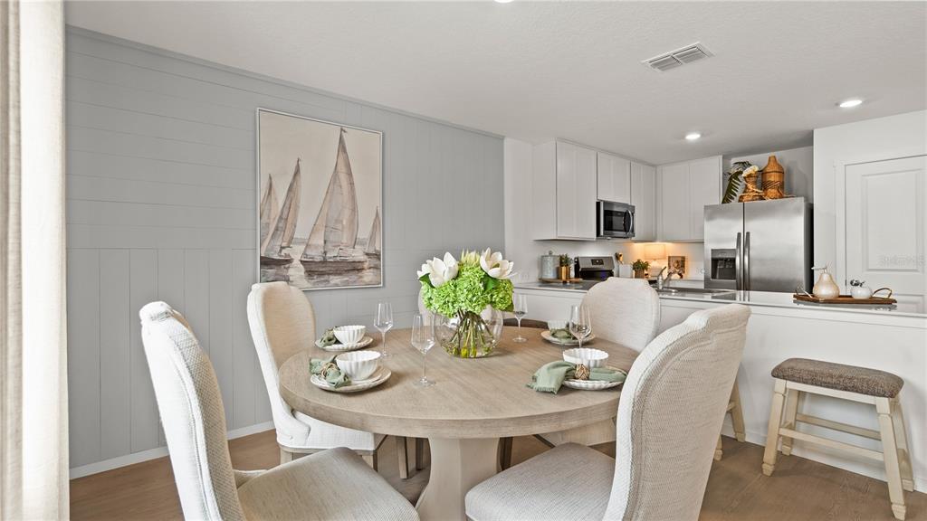 A dining area features a round wooden table with upholstered chairs and a sailboat painting — 4301 RIVERBEND BOULEVARD, HAINES CITY, FL