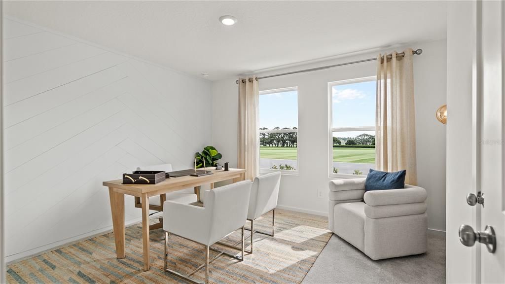 A home office features a wooden desk, two white chairs, and a patterned area rug — 4301 RIVERBEND BOULEVARD, HAINES CITY, FL