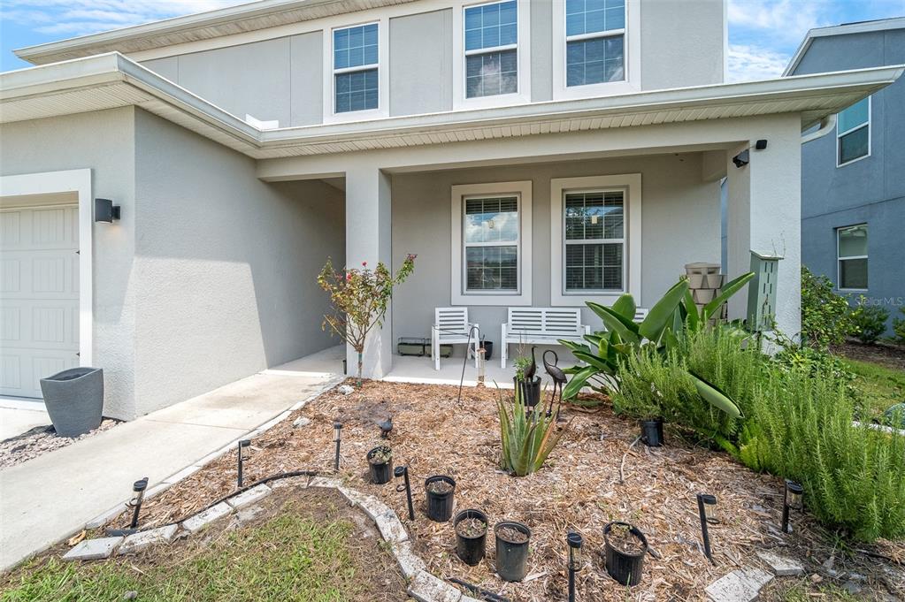 A two-story house exterior features a covered front porch, a small garden, and a garage — 2353 CRESCENT MOON STREET, KISSIMMEE, FL