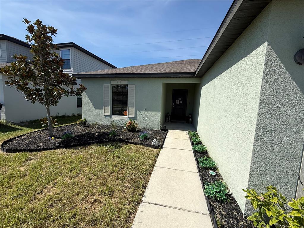 A light green stucco house features a concrete walkway leading to a recessed front entrance — 820 CHATHAM WALK DRIVE, RUSKIN, FL