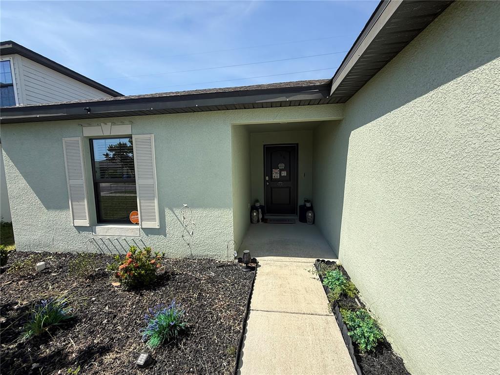 A light green stucco house exterior features a front door, walkway, and landscaped garden bed — 820 CHATHAM WALK DRIVE, RUSKIN, FL