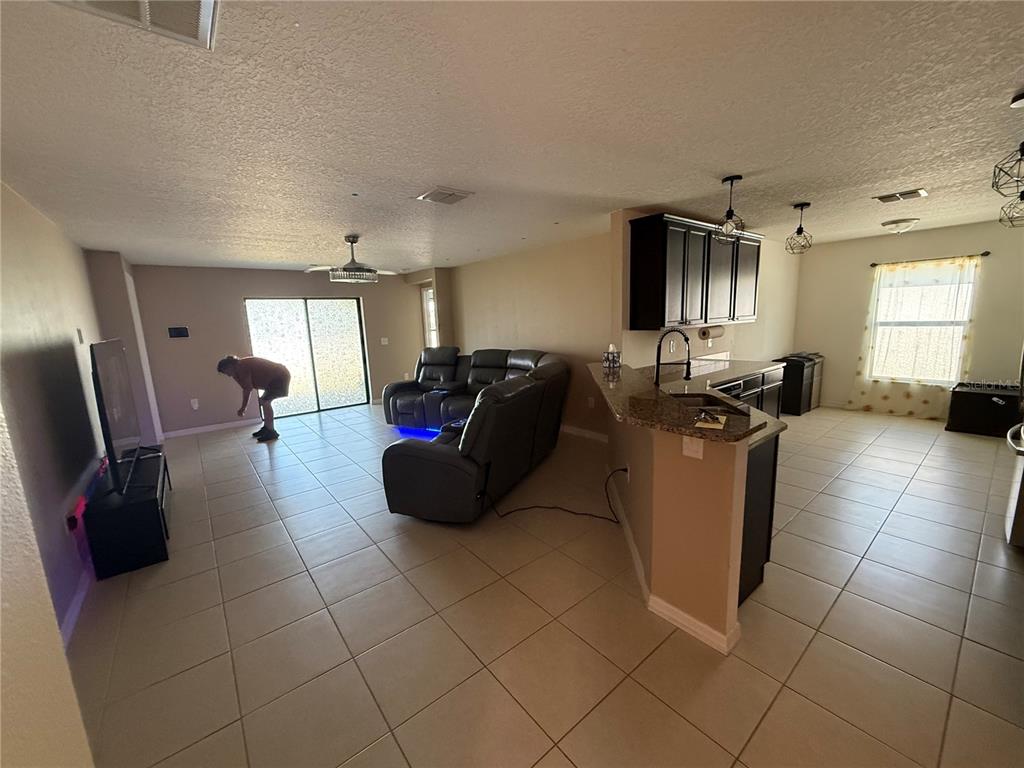 An open-concept living room and kitchen featuring tile flooring, dark cabinetry, and a sectional sofa — 820 CHATHAM WALK DRIVE, RUSKIN, FL