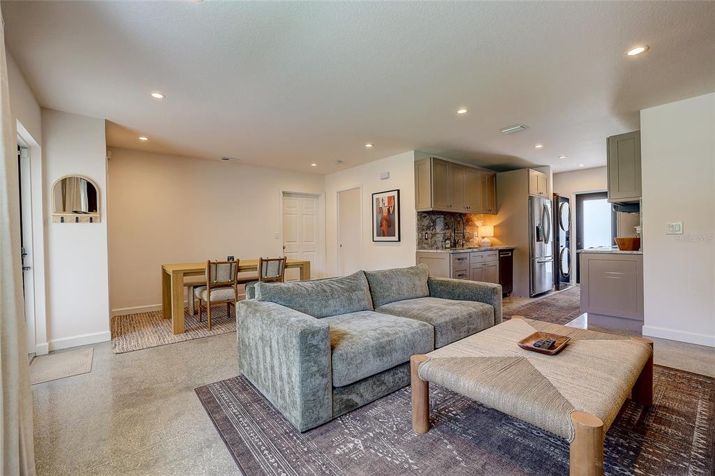 An open-concept living and dining area features a grey sofa, wooden table, and kitchen cabinetry — 2121 PALM TERRACE, SARASOTA, FL