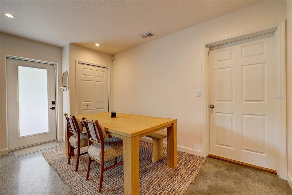 A dining area features a wooden table, chairs, a bench, and a rug on concrete floors — 2121 PALM TERRACE, SARASOTA, FL