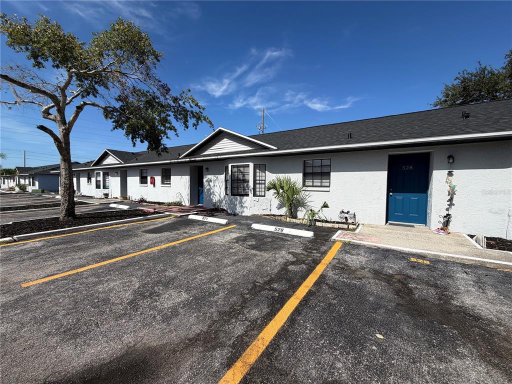 A single-story apartment building with a blue door and assigned parking spaces in front — 501 ST. MICHAELS WAY UNIT 524, TARPON SPRINGS, FL