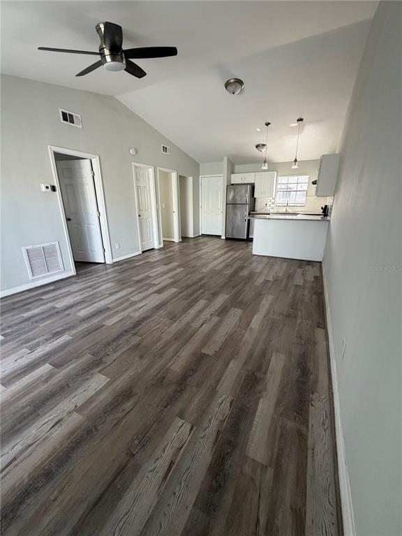 An open-concept living area features wood-look flooring, a vaulted ceiling with a fan, and a kitchen — 501 ST. MICHAELS WAY UNIT 524, TARPON SPRINGS, FL