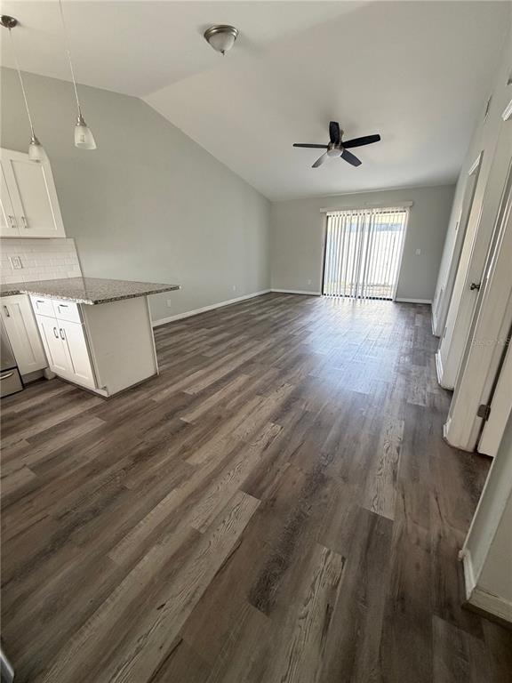 An open-concept kitchen and living area features light gray walls, white cabinets, and wood-look flooring — 501 ST. MICHAELS WAY UNIT 524, TARPON SPRINGS, FL