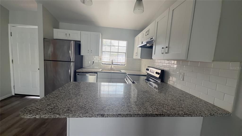 A kitchen features white cabinets, granite countertops, stainless steel appliances, and a subway tile backsplash — 501 ST. MICHAELS WAY UNIT 524, TARPON SPRINGS, FL