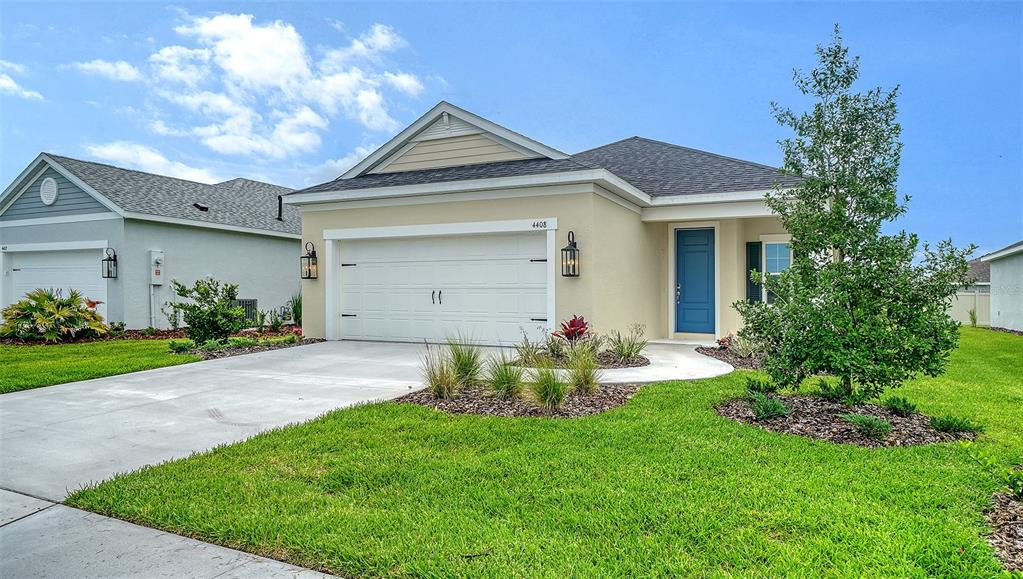 A single-story house with a beige exterior, a two-car garage, and a blue front door — 4408 SPOON BLADE DRIVE, PARRISH, FL