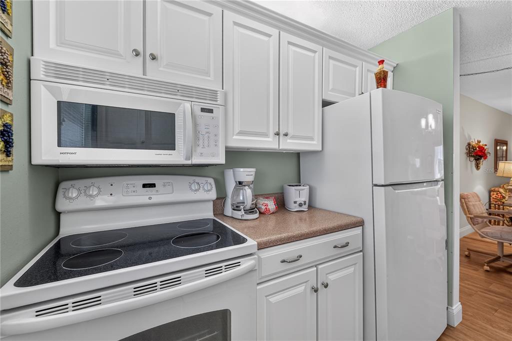 A bedroom features a bed with a geometric quilt, a wooden dresser, and a window — 4801 AIRPORT ROAD UNIT 119, ZEPHYRHILLS, FL