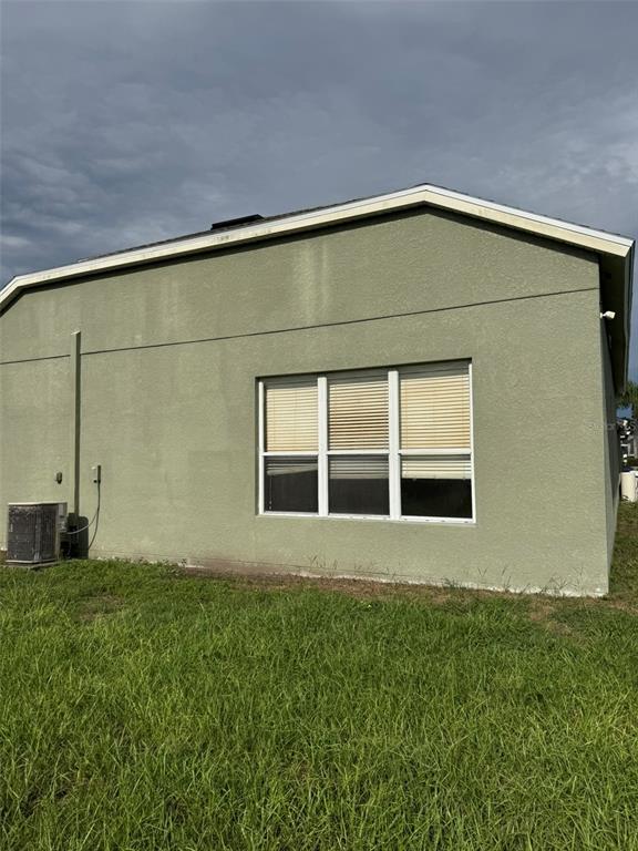 The exterior side wall of a house features a large window and an air conditioning unit — 5035 ALDERBROOK, LAND O LAKES, FL