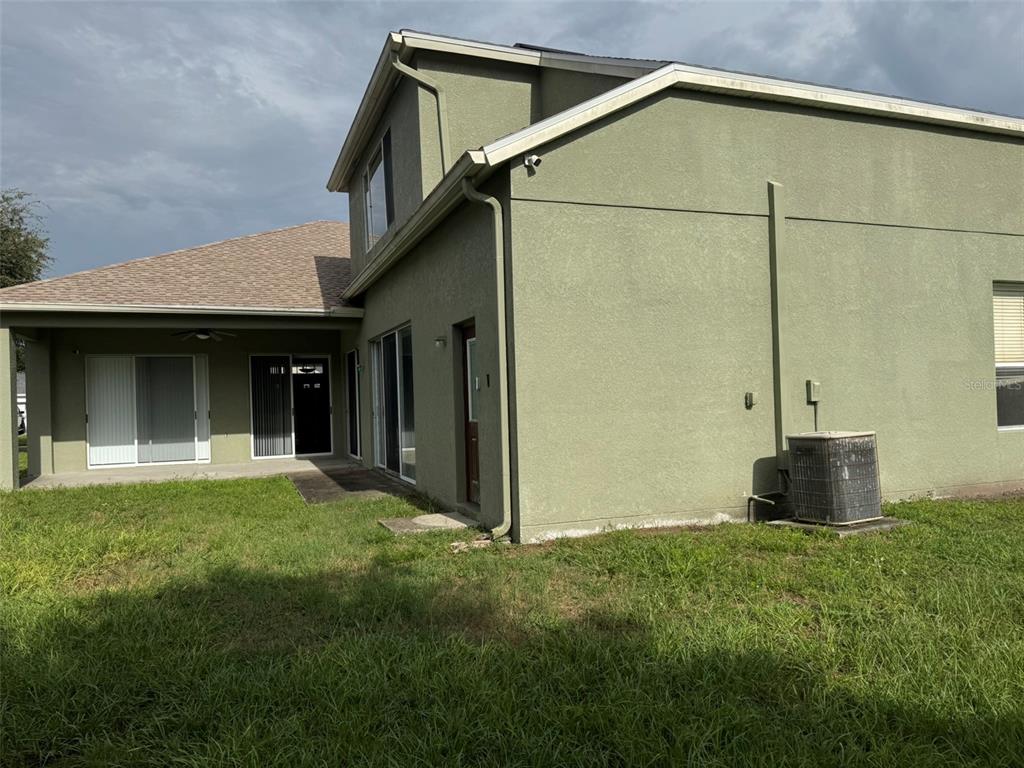 The exterior of a two-story green stucco house features a covered patio and an air conditioner — 5035 ALDERBROOK, LAND O LAKES, FL