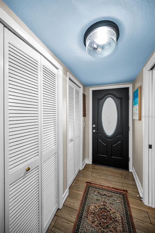 A covered balcony features two chairs, a small table, and arched openings overlooking a parking lot — 2384 TAHITIAN LANE UNIT 22, CLEARWATER, FL