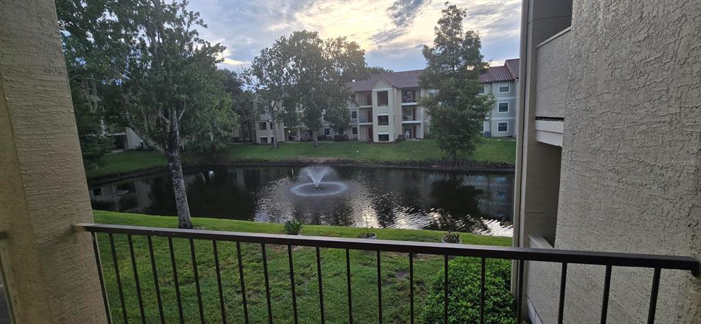 A balcony view overlooks a pond with a fountain and surrounding apartment buildings — 3004 PARKWAY BOULEVARD UNIT 210, KISSIMMEE, FL