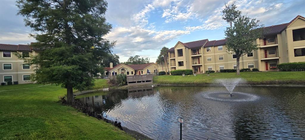 A pond with a fountain sits in front of apartment buildings and a clubhouse — 3004 PARKWAY BOULEVARD UNIT 210, KISSIMMEE, FL