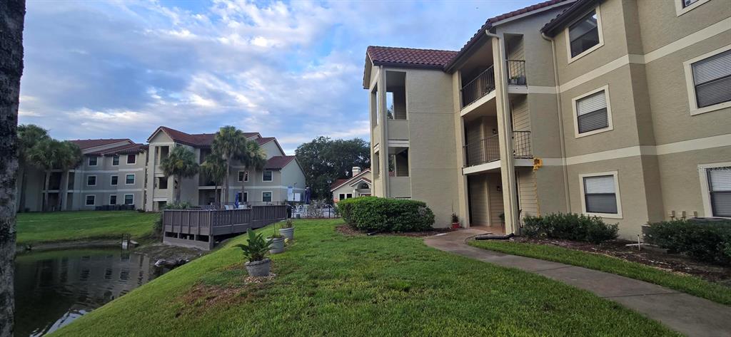 Exterior view of multi-story apartment buildings with balconies, a small pond, and landscaped grounds — 3004 PARKWAY BOULEVARD UNIT 210, KISSIMMEE, FL