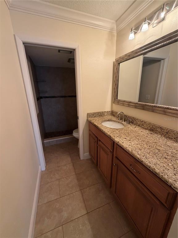 A bathroom features a granite vanity, wooden cabinets, a framed mirror, and a tiled shower — 2606 29TH AVE W UNIT 12, BRADENTON, FL