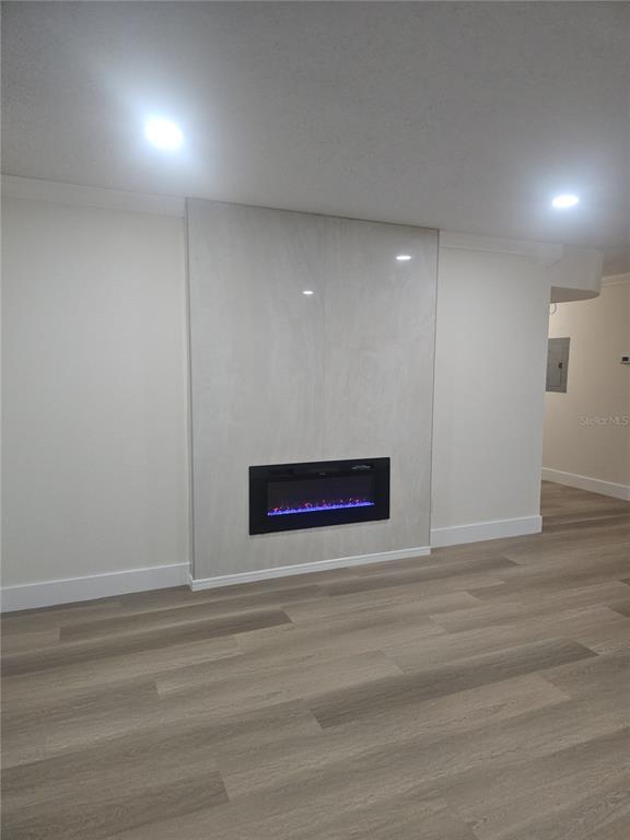 A modern living room features light wood-look flooring and a fireplace set in a tiled wall — 7210 N MANHATTAN AVENUE UNIT 1724, TAMPA, FL