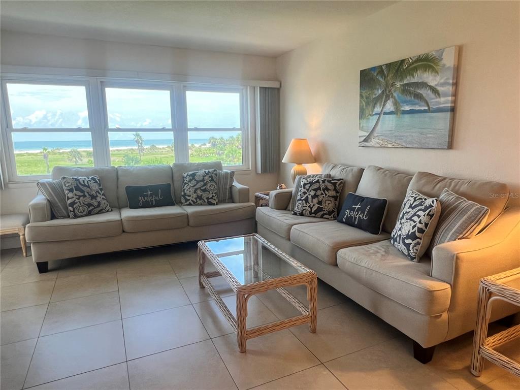A dining area with a glass table and wicker chairs sits before a kitchen with cabinets — 1230 GULF BOULEVARD UNIT 306, CLEARWATER BEACH, FL