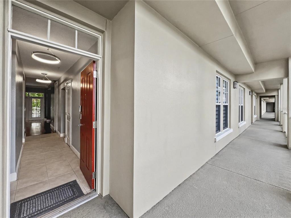 An open red door leads into a tiled entryway from a concrete outdoor walkway — 1411 CELEBRATION AVENUE UNIT 206, CELEBRATION, FL