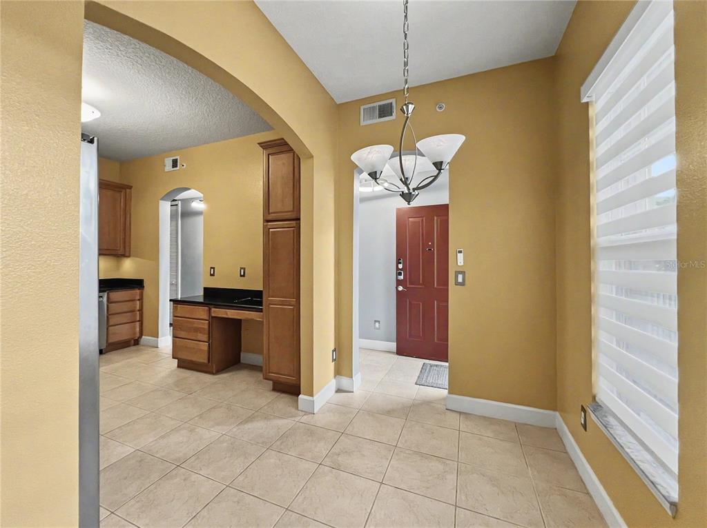 A dining area with tile flooring leads to a kitchen with wood cabinetry and a desk — 1411 CELEBRATION AVENUE UNIT 206, CELEBRATION, FL