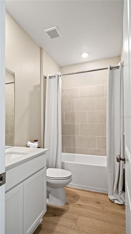 A bathroom features a white vanity, a toilet, and a bathtub with beige tiled walls — 2866 PIONEER TRAIL, EAGLE LAKE, FL