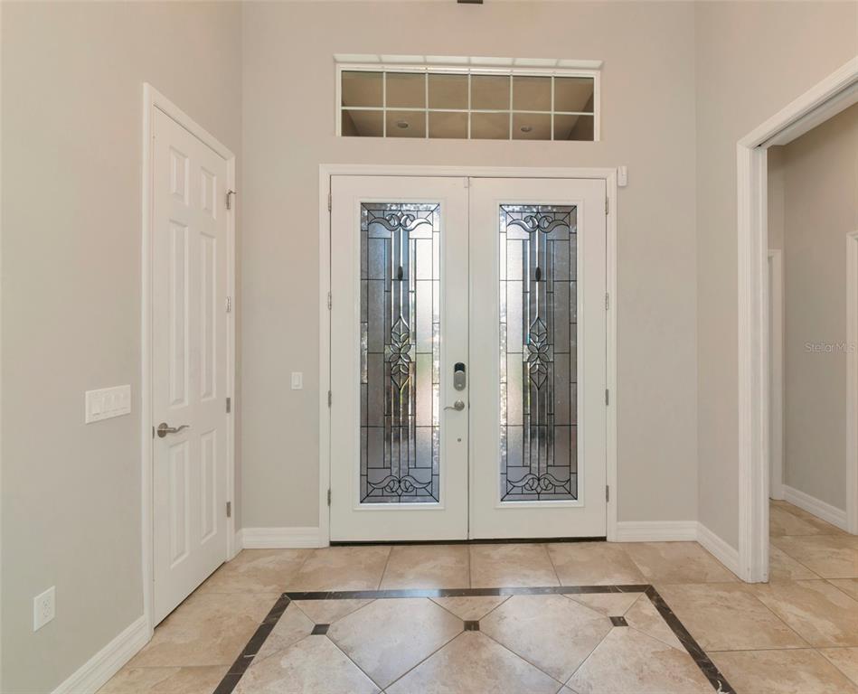An entryway features double glass-paneled doors, a transom window, and light-colored tile flooring — 15208 21ST AVENUE E, BRADENTON, FL