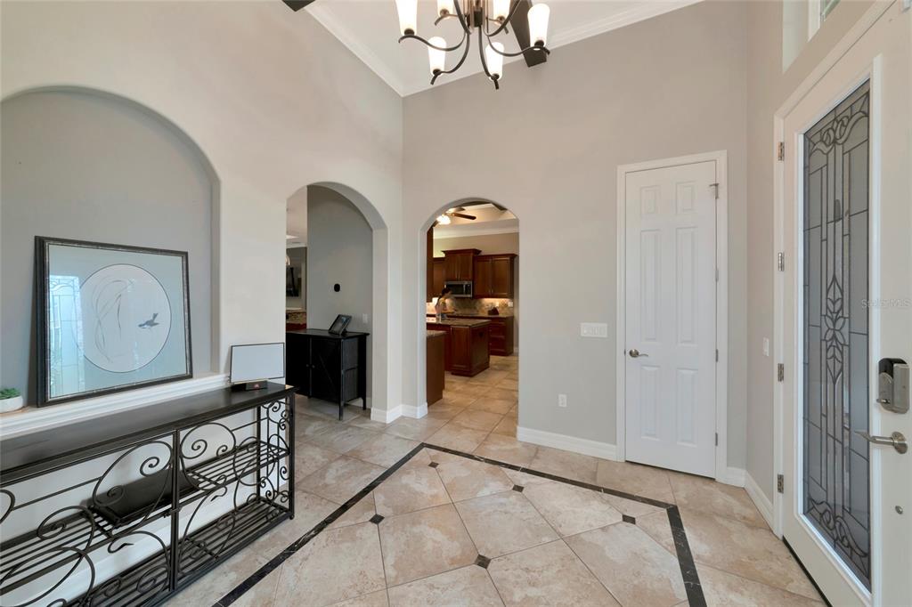 A tiled entryway features arched doorways, a decorative console table, and a glass-paneled front door — 15208 21ST AVENUE E, BRADENTON, FL