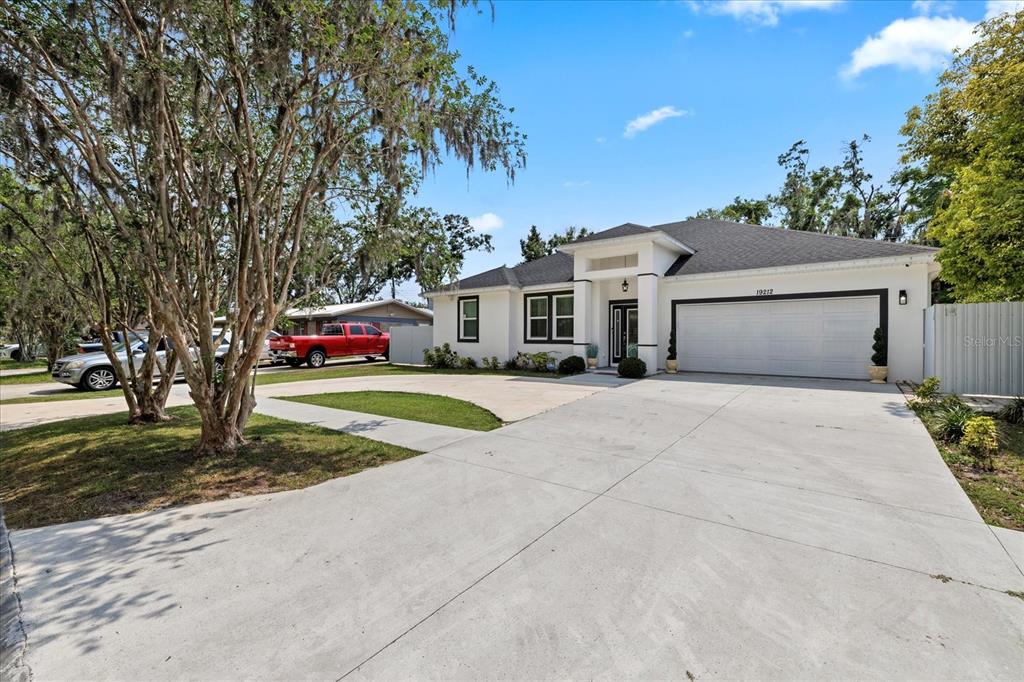 A white single-story house with a two-car garage and a large concrete driveway — 19212 SUNLAKE BOULEVARD, LUTZ, FL