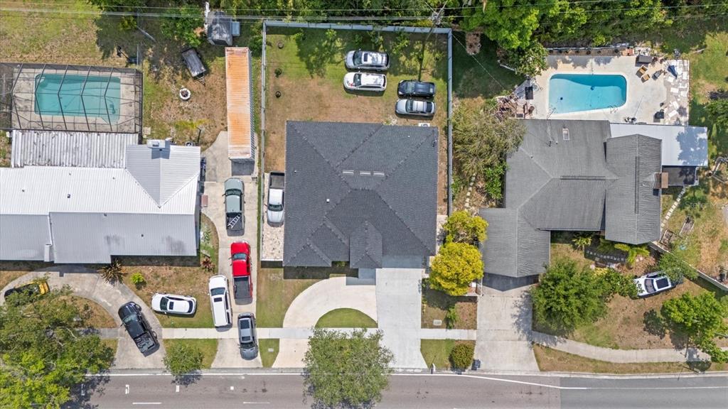 An aerial view shows three residential properties with swimming pools, driveways, and parked vehicles — 19212 SUNLAKE BOULEVARD, LUTZ, FL