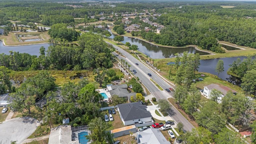 An aerial view shows a suburban neighborhood with houses, swimming pools, and a divided road — 19212 SUNLAKE BOULEVARD, LUTZ, FL