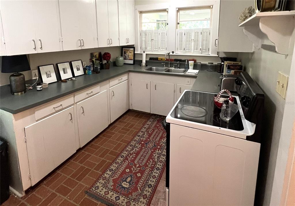 A kitchen features white cabinets, dark countertops, a double sink, and a red patterned rug — 1617 NW 7TH PLACE, GAINESVILLE, FL