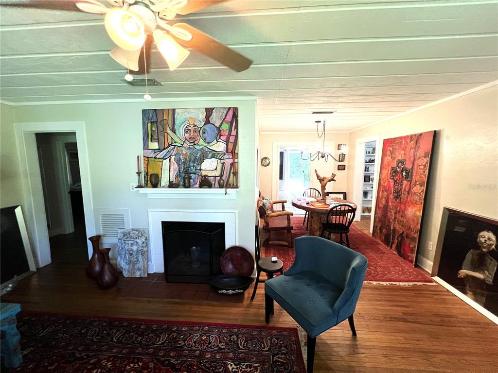 A living room with a fireplace, hardwood floors, area rugs, and several large art pieces — 1617 NW 7TH PLACE, GAINESVILLE, FL