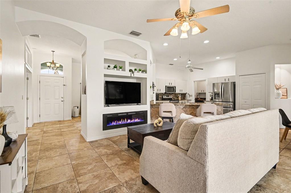 A living room with tile floors, a fireplace, a television, and an open kitchen — 1754 TRIBUTORY LN, PORT ORANGE, FL