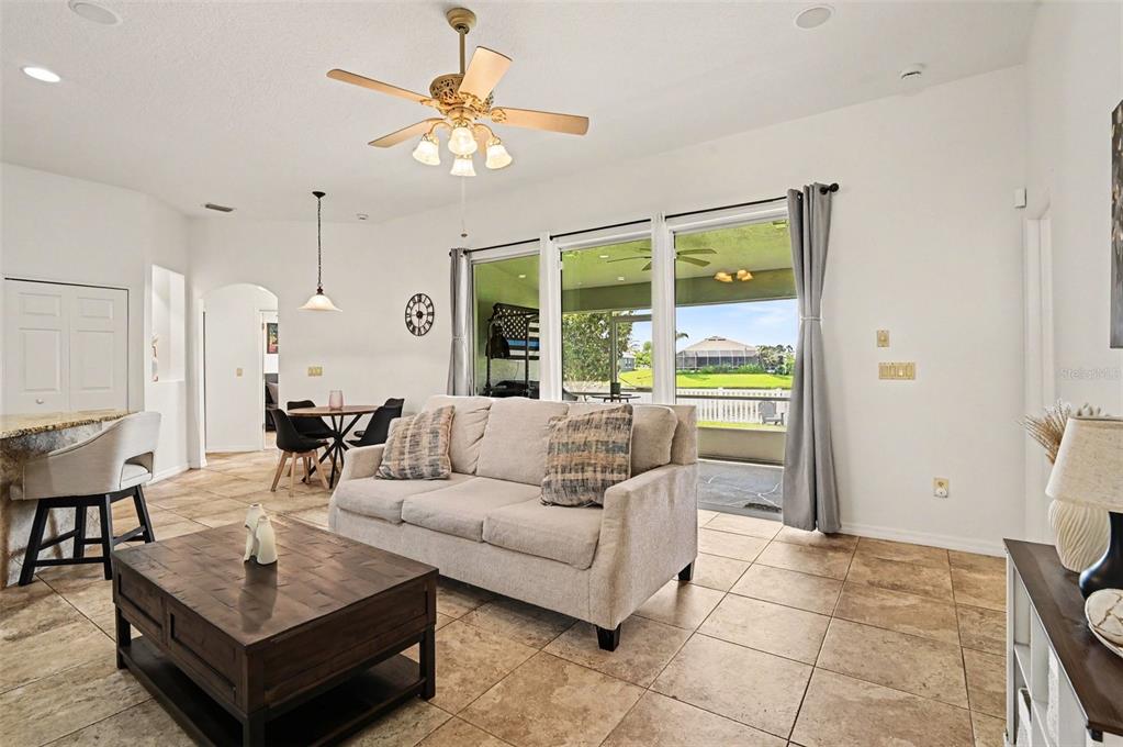 A living room with tile floors, a beige sofa, a coffee table, and sliding glass doors — 1754 TRIBUTORY LN, PORT ORANGE, FL