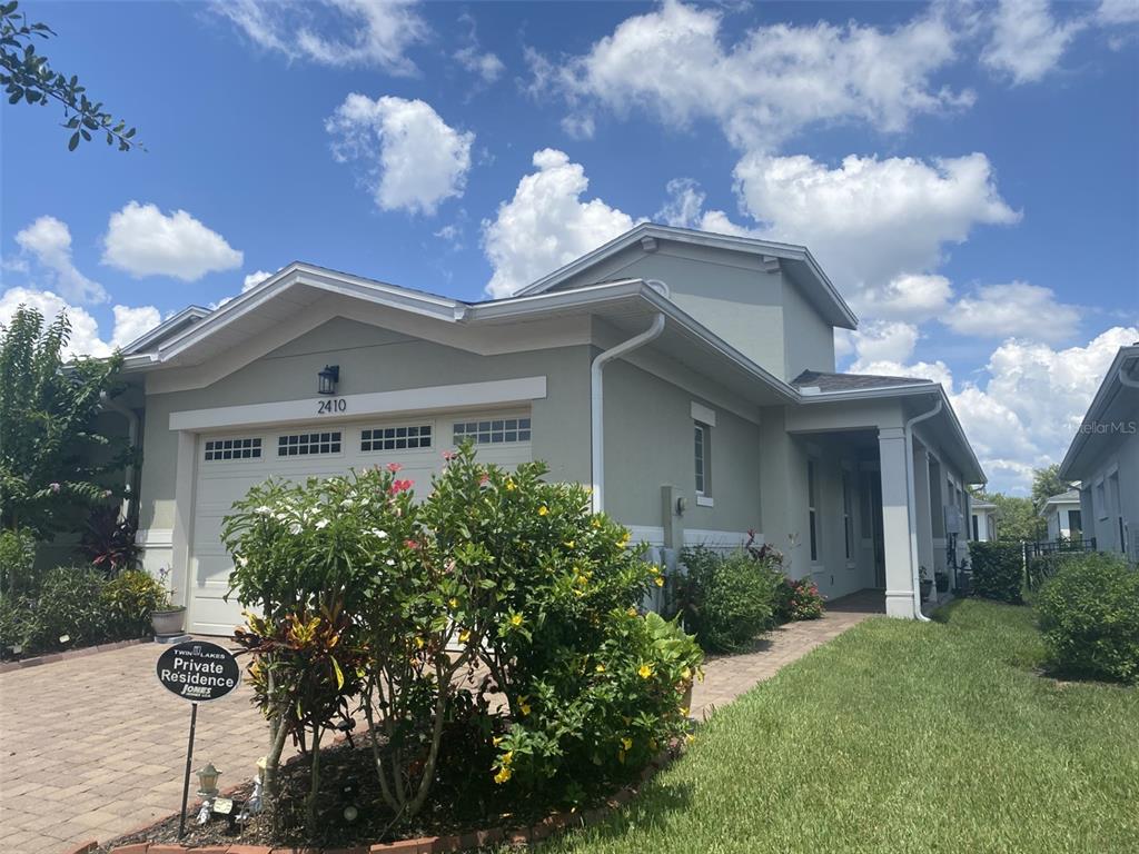A single-story house with a light green exterior, a two-car garage, and a paved walkway — 2410 DATURA LOOP, ST CLOUD, FL