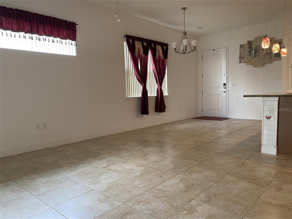 A tiled dining area features a chandelier, window treatments, and an adjacent kitchen counter — 2410 DATURA LOOP, ST CLOUD, FL