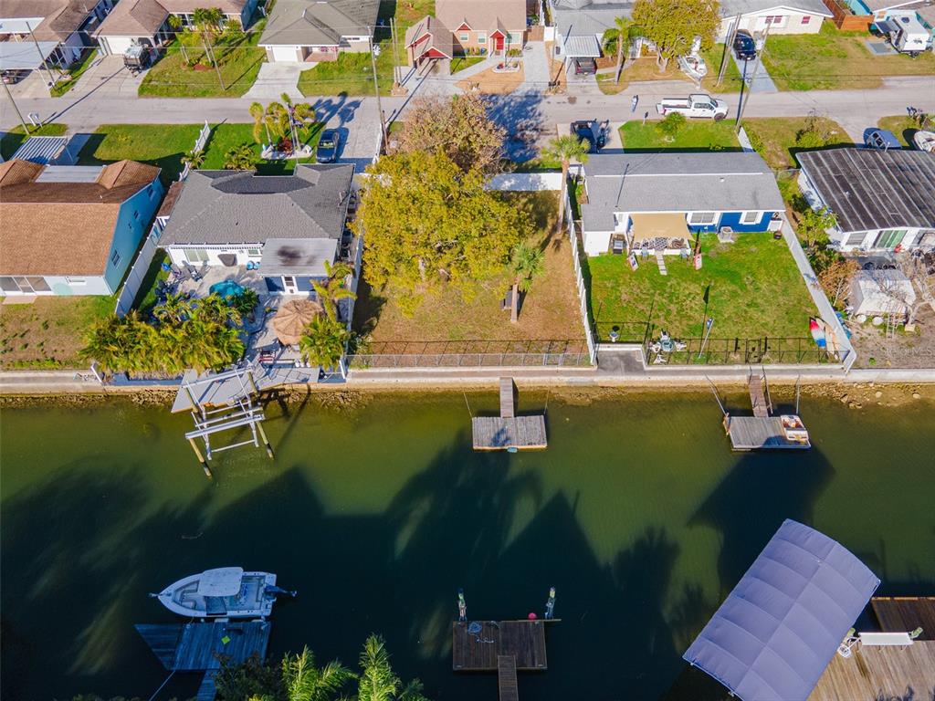 An aerial view shows three waterfront residential properties with private docks along a canal — 13916 BERKOWITZ AVENUE, HUDSON, FL