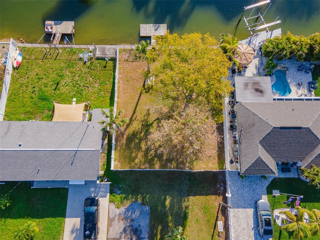 An aerial view shows a vacant waterfront lot situated between two houses with private docks — 13916 BERKOWITZ AVENUE, HUDSON, FL