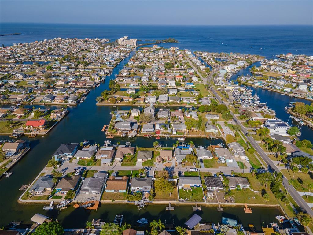 An aerial view shows a coastal neighborhood with houses situated along multiple residential canals — 13916 BERKOWITZ AVENUE, HUDSON, FL
