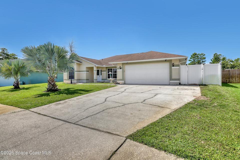 A single-story house with a two-car garage, a concrete driveway, and two palm trees — 3975 TANGLE DRIVE, TITUSVILLE, FL
