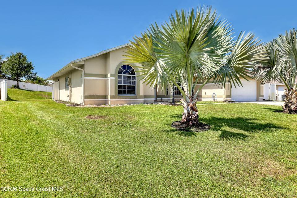 A single-story house with a beige exterior, arched window, and two large palm trees — 3975 TANGLE DRIVE, TITUSVILLE, FL