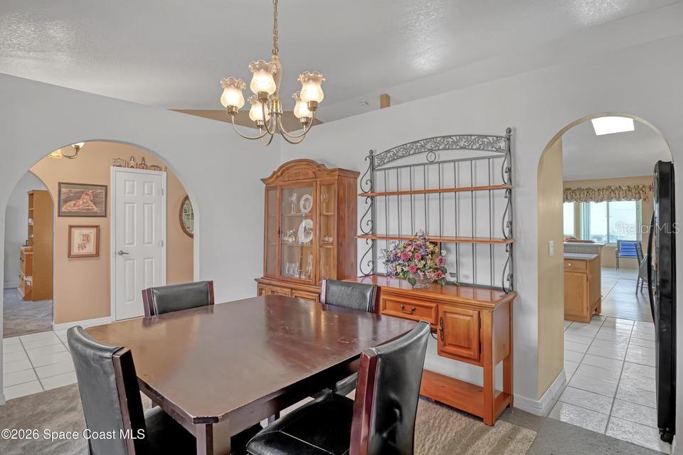 A dining room features a wooden table, chairs, a hutch, and arched doorways — 3975 TANGLE DRIVE, TITUSVILLE, FL