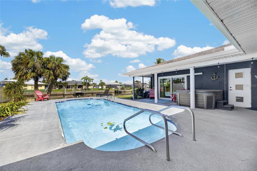 A backyard features a swimming pool, a hot tub, and a patio overlooking a canal — 6314 WISTERIA LANE, APOLLO BEACH, FL
