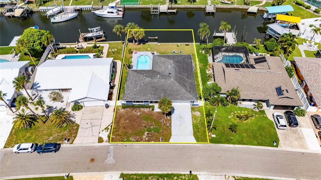 An aerial view shows a waterfront house with a pool, driveway, and backyard lawn — 6314 WISTERIA LANE, APOLLO BEACH, FL
