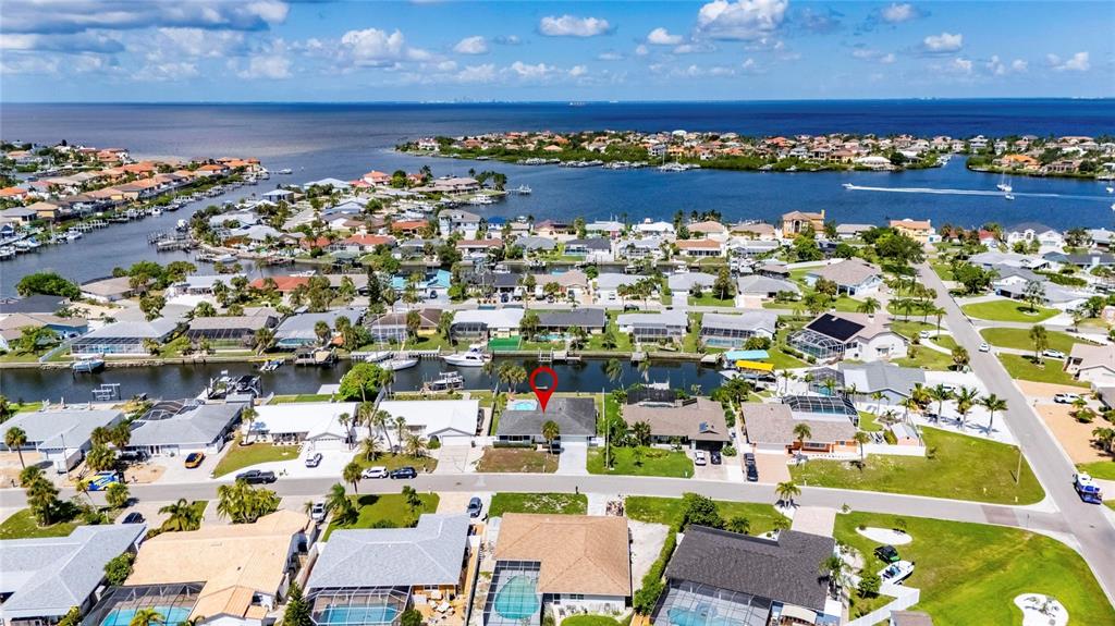 An aerial view shows a residential neighborhood with houses, canals, and a large body of water — 6314 WISTERIA LANE, APOLLO BEACH, FL