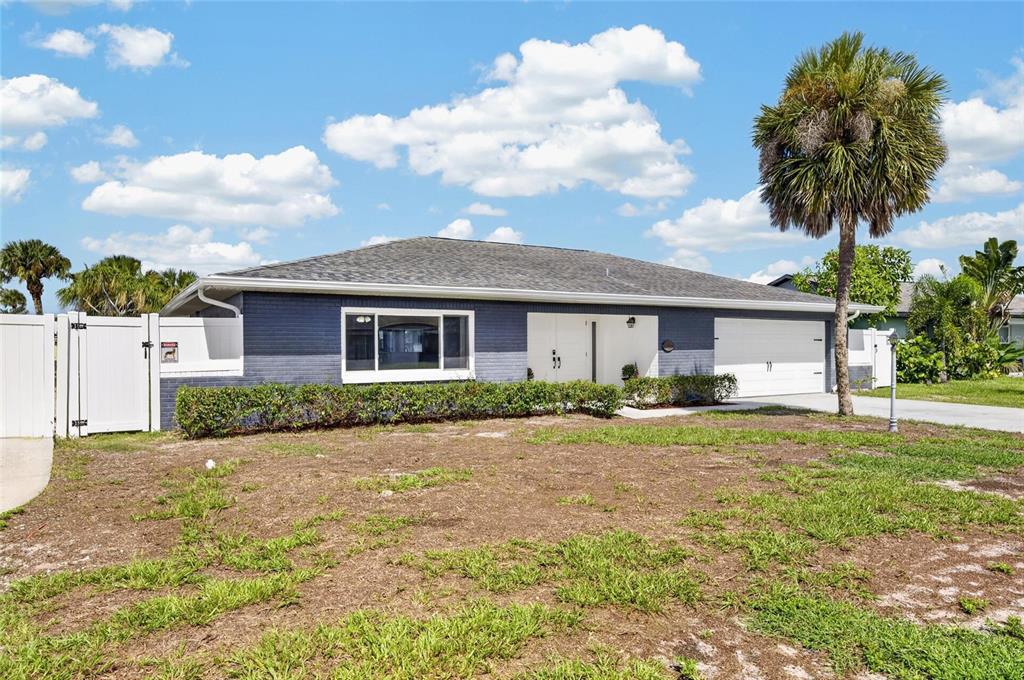 A single-story house with blue brick siding, a white garage, and a palm tree — 6314 WISTERIA LANE, APOLLO BEACH, FL