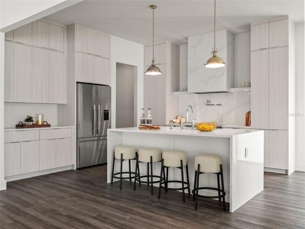A modern kitchen features light wood cabinetry, a white quartz island, and four bar stools — 1320 CLOVERLAWN AVENUE, ORLANDO, FL
