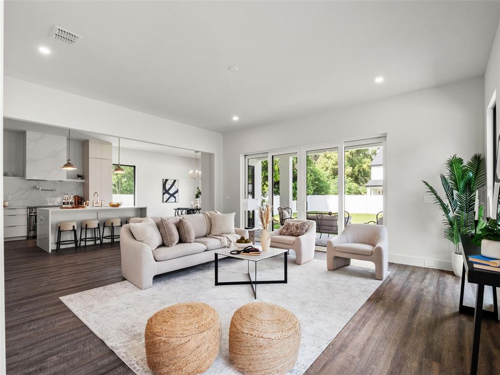 A bright, open-concept living room features a neutral sofa, two armchairs, and a modern kitchen — 1320 CLOVERLAWN AVENUE, ORLANDO, FL